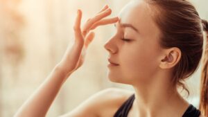 Woman touching her third eye to increase intuition with positive affirmations