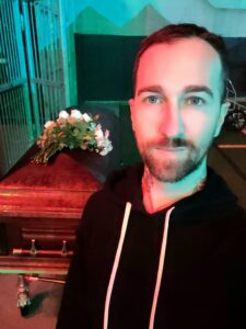 Chris Bennett at night in front of a coffin on the set of School Spirits