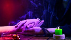 Psychic reader with green candle and purple light, a warning about scam psychics