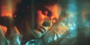A sleeper bathed in soft light during a visitation dream from a loved one in spirit