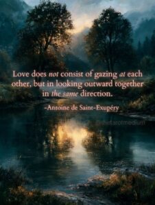 Two trees on opposite banks of a still lake at dawn, their reflections nearly meeting in the water, teal and gold, with the Antoine de Saint-Exupery quote "Love does not consist of gazing at each other, but in looking outward together in the same direction."